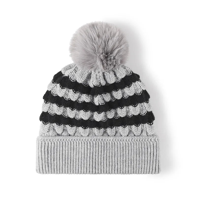 Gray knit beanie with black scalloped stripes and a gray pom pom.