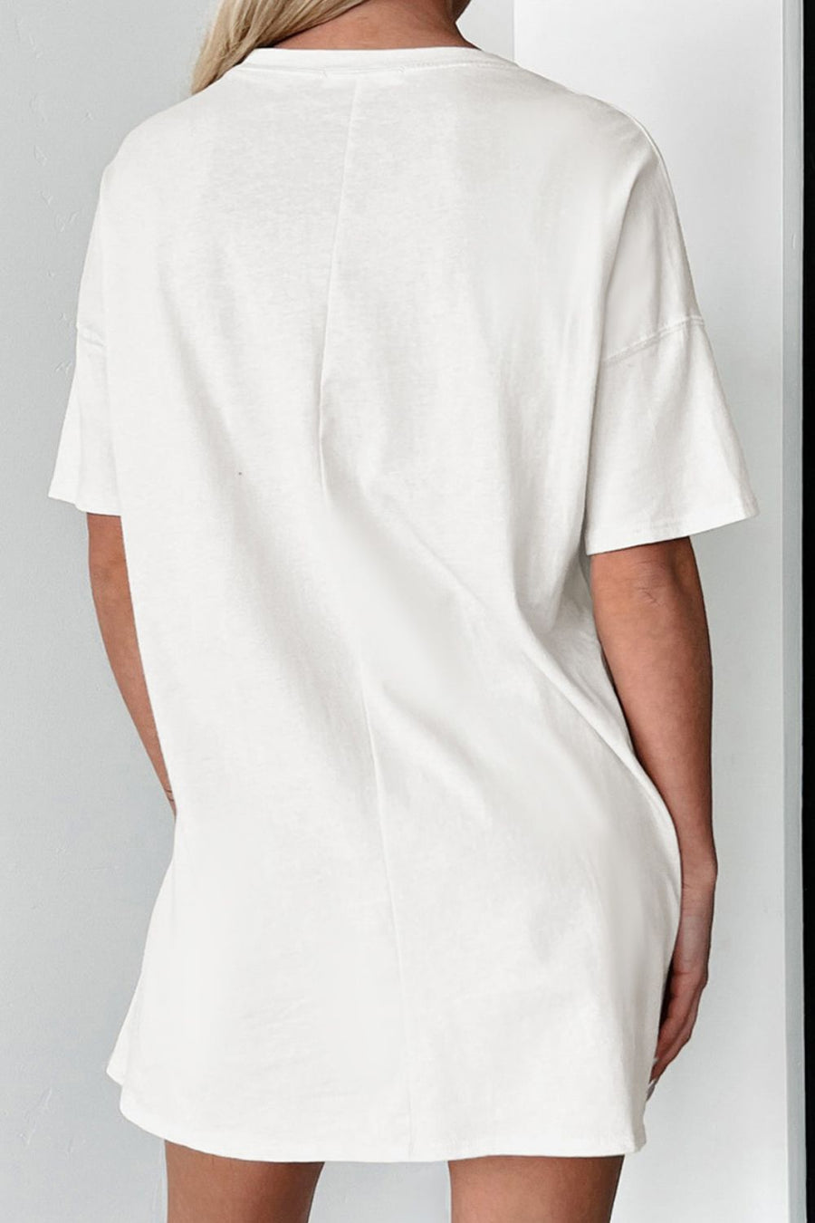 White oversized tee dress with short sleeves and a relaxed fit.