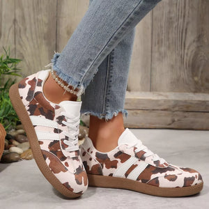 Trendy cow print low-top sneakers with white stripes and brown soles.