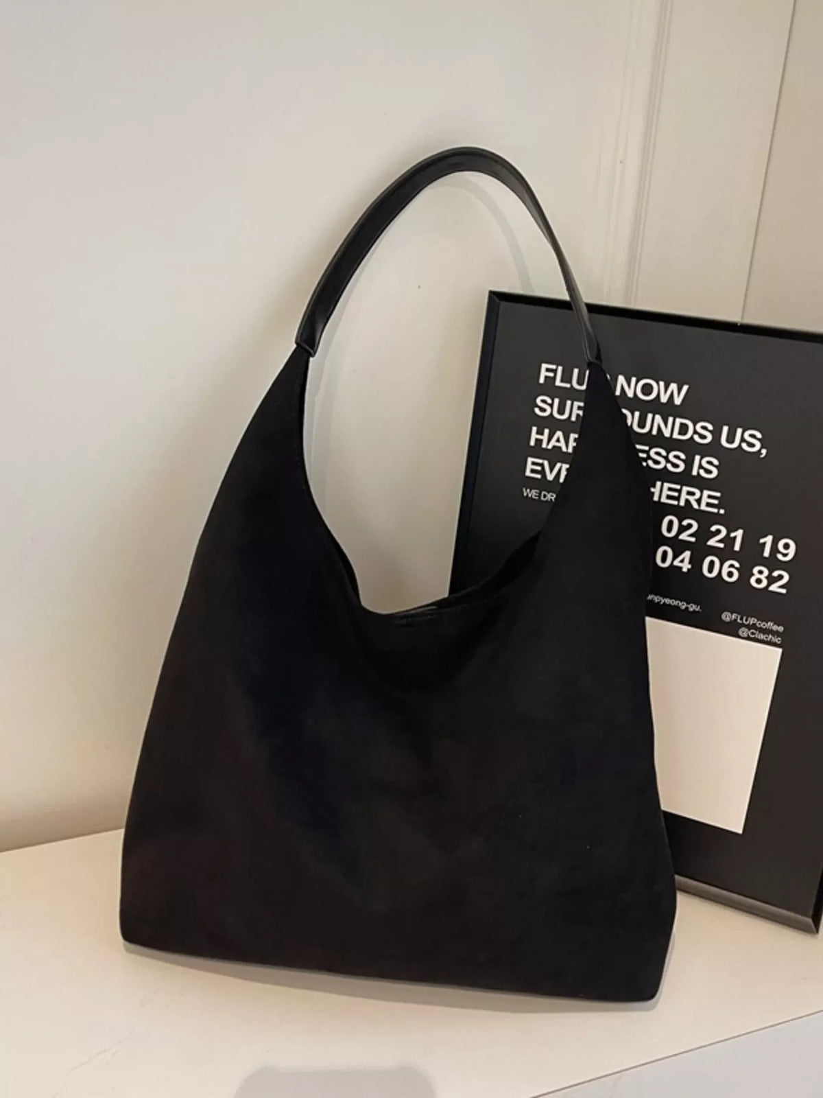 Black suede hobo bag with a single strap and slouchy silhouette.