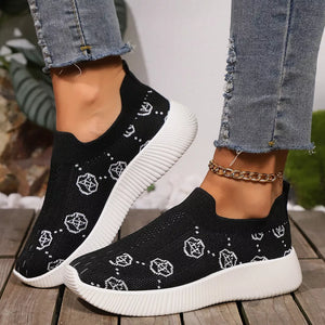 Black mesh slip-on sneakers with white geometric pattern and white soles.
