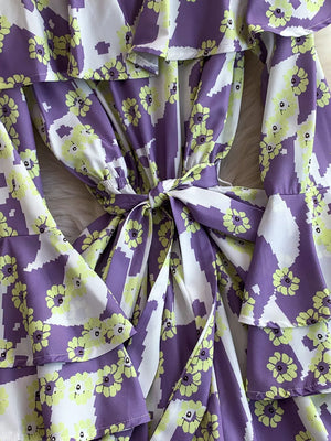 Purple floral print off-shoulder ruffled romper with tie waist and bell sleeves.