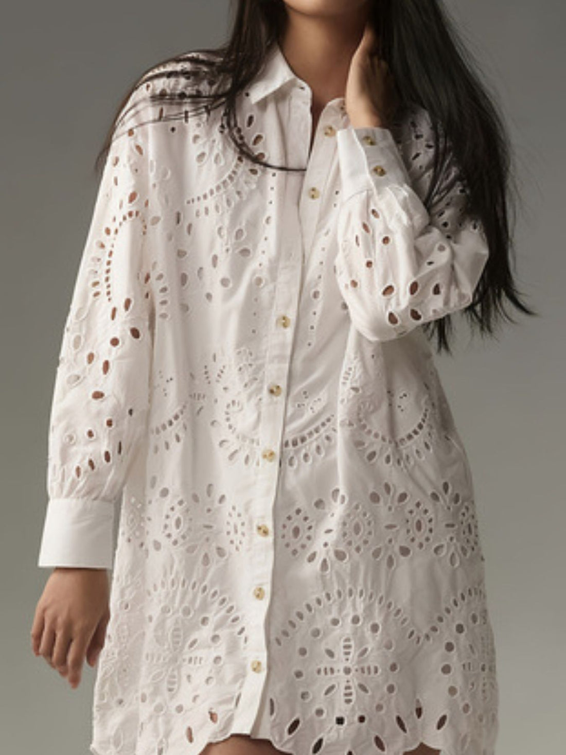 White eyelet button-up longline shirt with cutouts and gold buttons.