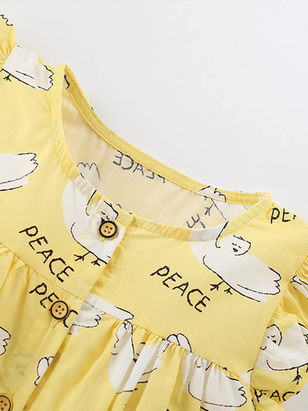 Yellow cotton blend toddler dress with dove print and ruffle sleeves.