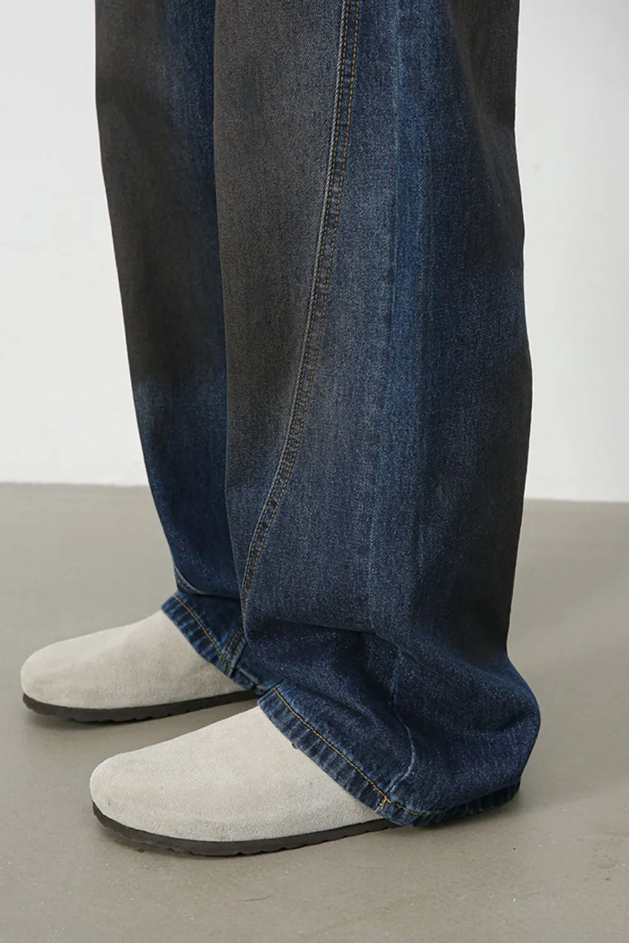 Faded panel wide-leg denim trousers in medium wash with visible seams.