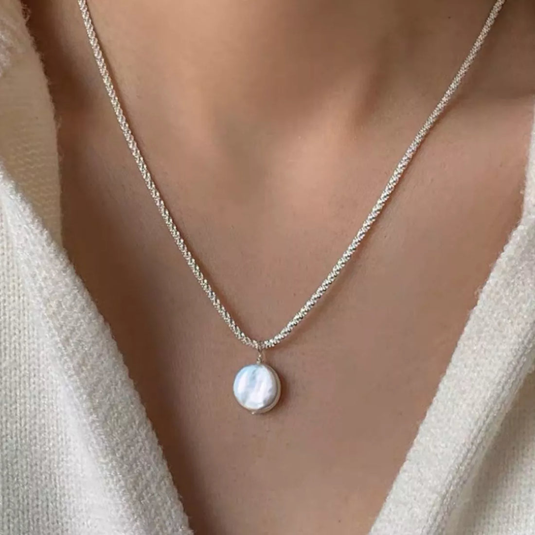 Elegant silver necklace with a flat pearl pendant.