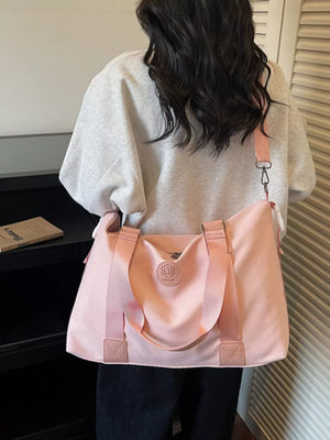 Chic perforated large duffle bag in pink with dual handles and a crossbody strap.