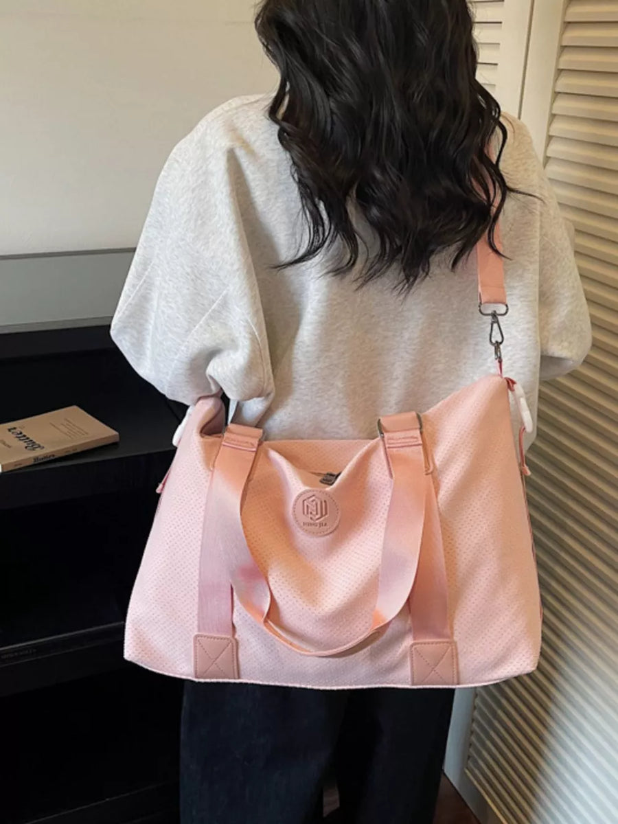 Chic perforated large duffle bag in pink with dual handles and a crossbody strap.