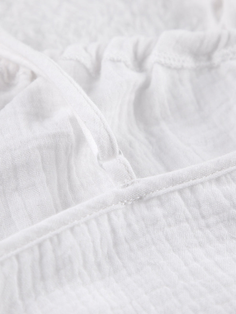 White cotton cami pajama top detail with adjustable strap and textured fabric.