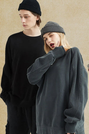 Oversized sweatshirt in dark gray with raw-edge seams and crew neck, styled casually.