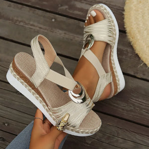 Beige espadrille wedges with metallic accents and a ring detail.