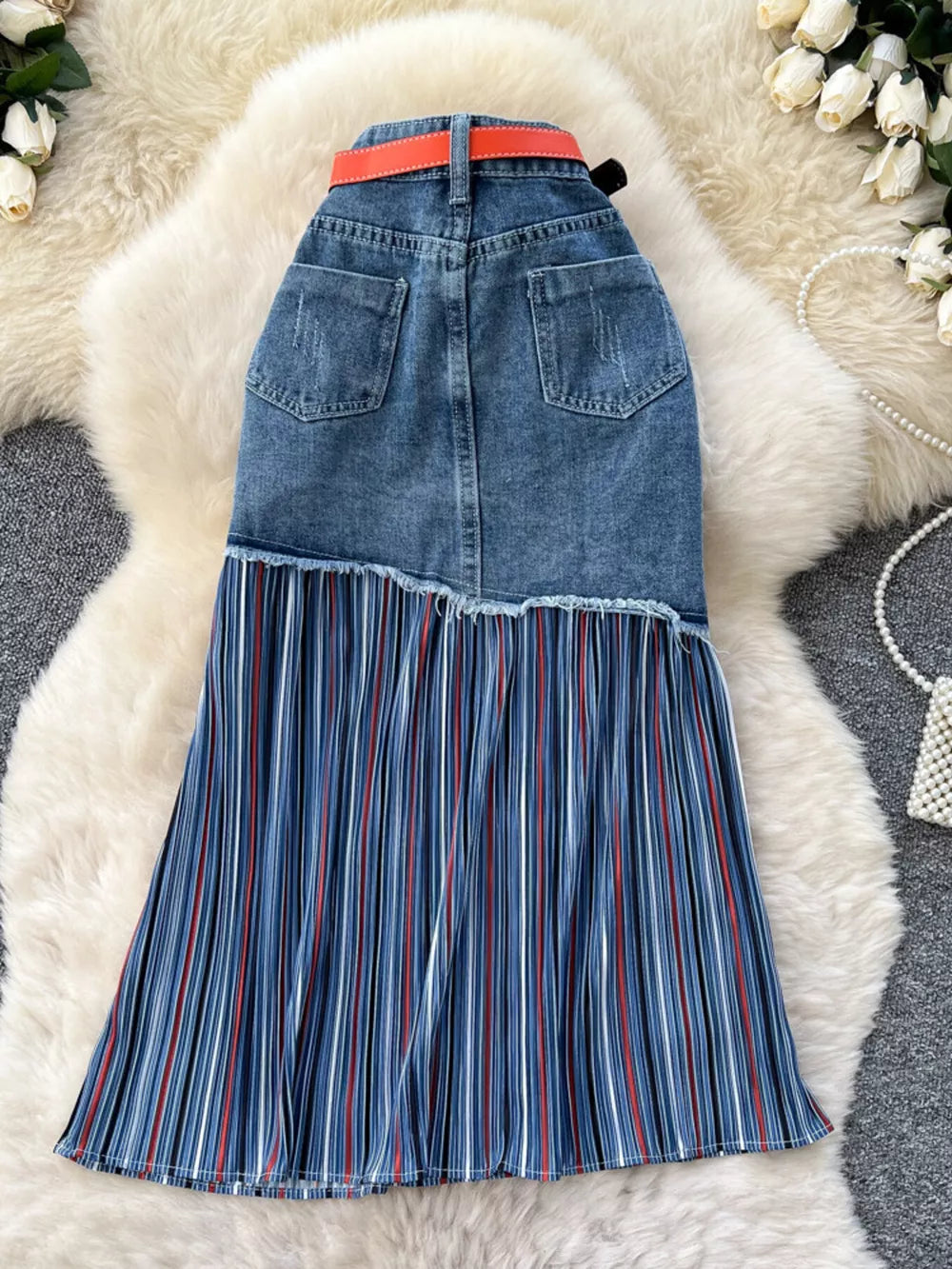 Patchwork denim midi skirt with red and white striped pleated hem and orange belt.