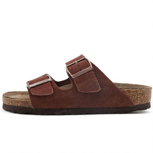Dark brown suede slide sandals with two adjustable buckle straps and cork footbed.