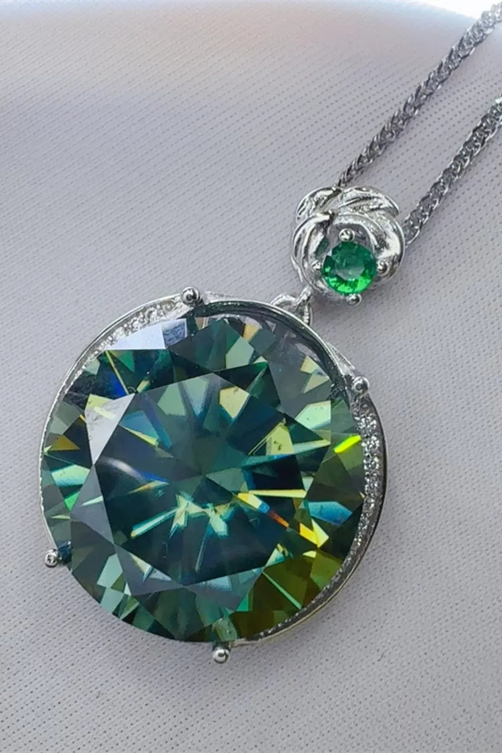 Dark green moissanite and sterling silver necklace with a floral bail and small emerald accent.
