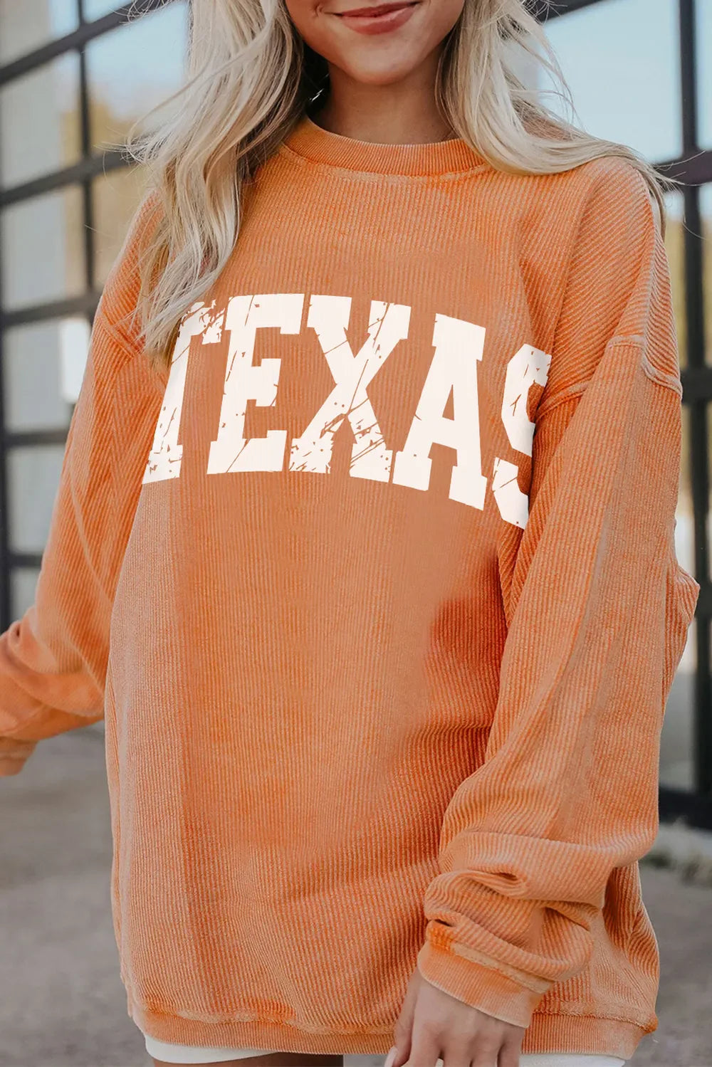 Textured sherbet crewneck sweatshirt with distressed white "Texas" graphic.