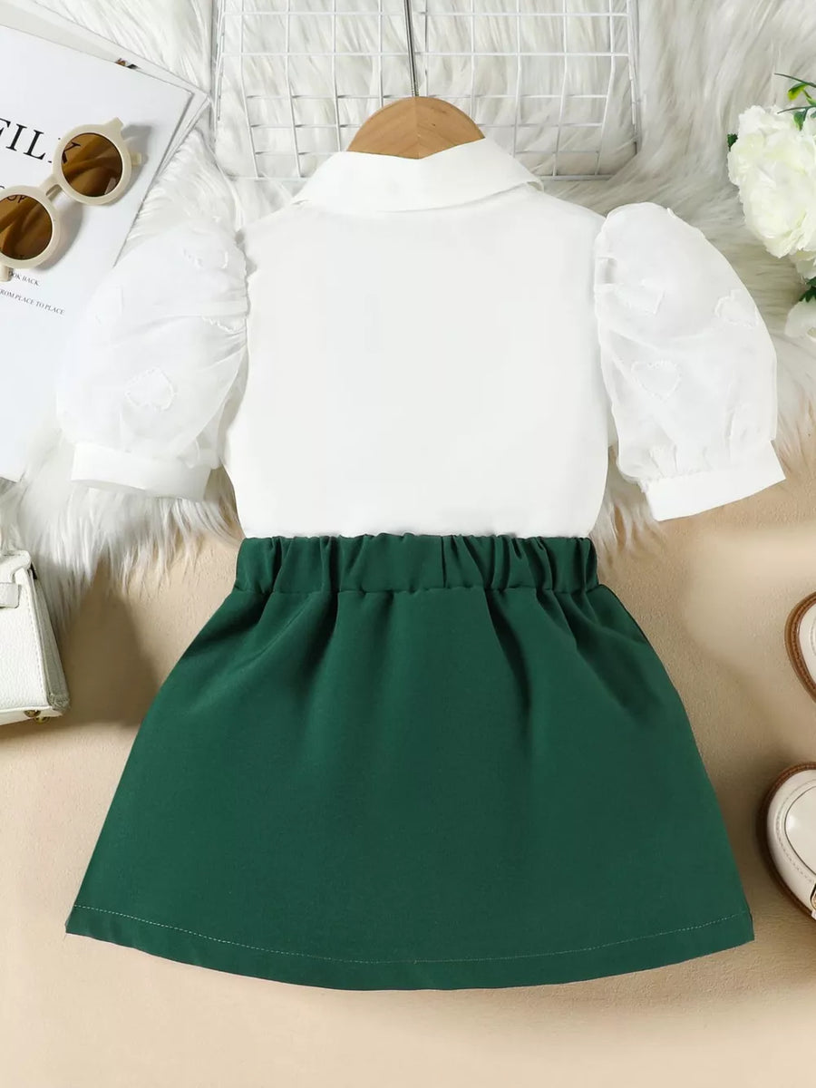 Baby girl green skirt and white puff sleeve top with heart pattern detail.
