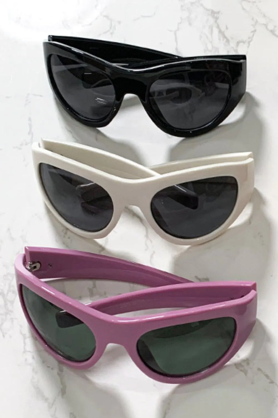 Sporty shield sunglasses in black, beige, and dusty pink with dark lenses.