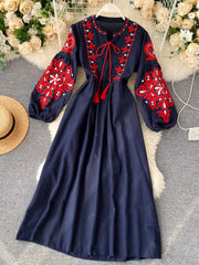 Navy blue maxi dress with red embroidery, balloon sleeves, and tie neck
