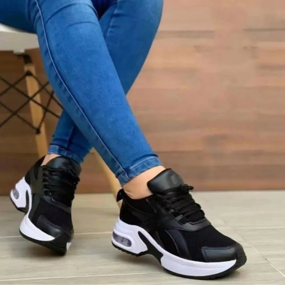 Black lace up air cushion sneakers with chunky white soles and visible air pockets.