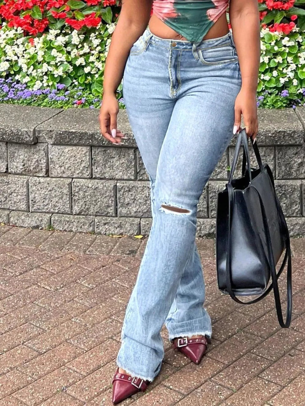 Light blue distressed flare jeans with raw hem and a knee rip.