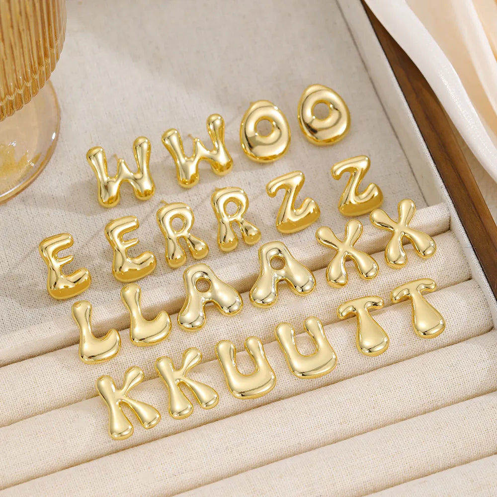 Alphabet stud earrings in gold, featuring bubble letter designs for casual wear.