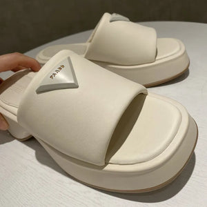 Ivory platform slides with geometric branding detail and thick sole.