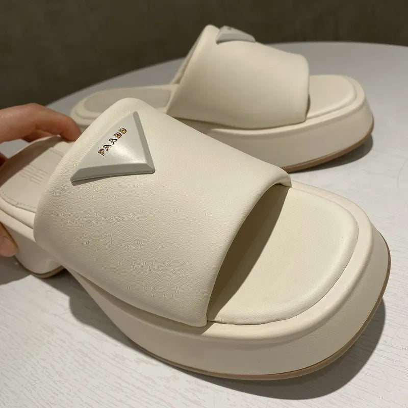 Ivory platform slides with geometric branding detail and thick sole.