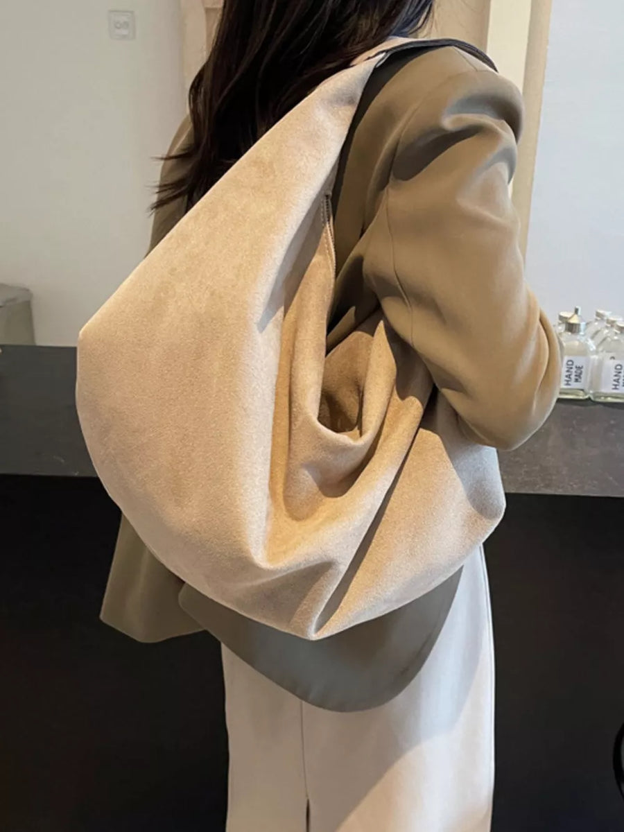 Spacious off-white suede shoulder bag with zipper detail, worn on shoulder.