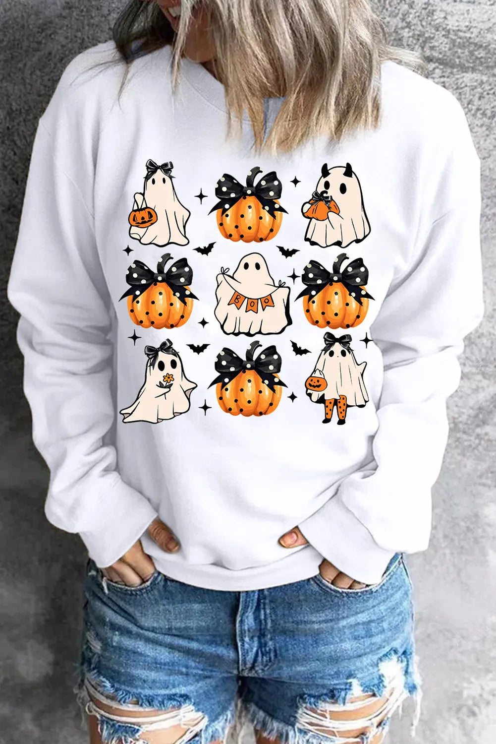 White crewneck sweatshirt with a spooky patchwork graphic of ghosts and pumpkins.