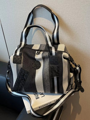 Chic striped medium duffle bag with black and white stripes and a detachable strap.