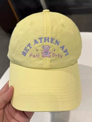 Yellow baseball cap with embroidered teddy bear and text detail