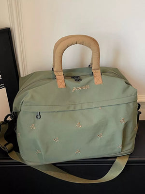 Green duffel bag with embroidered bows and tan handles