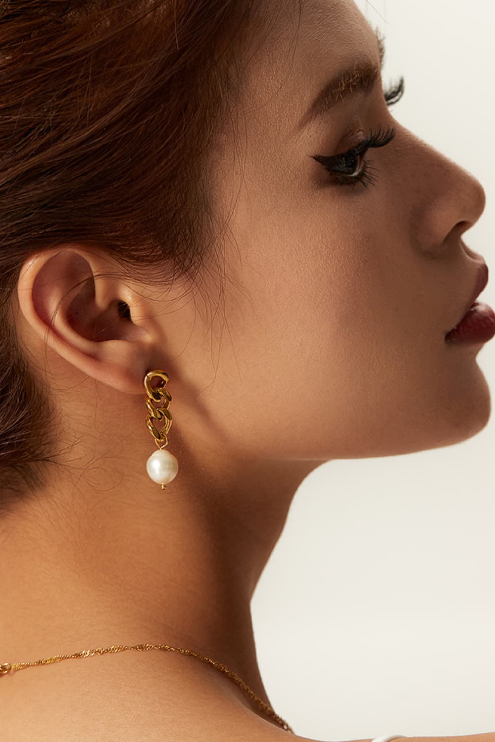 Gold chunky chain and pearl drop earrings with a modern, bold design.