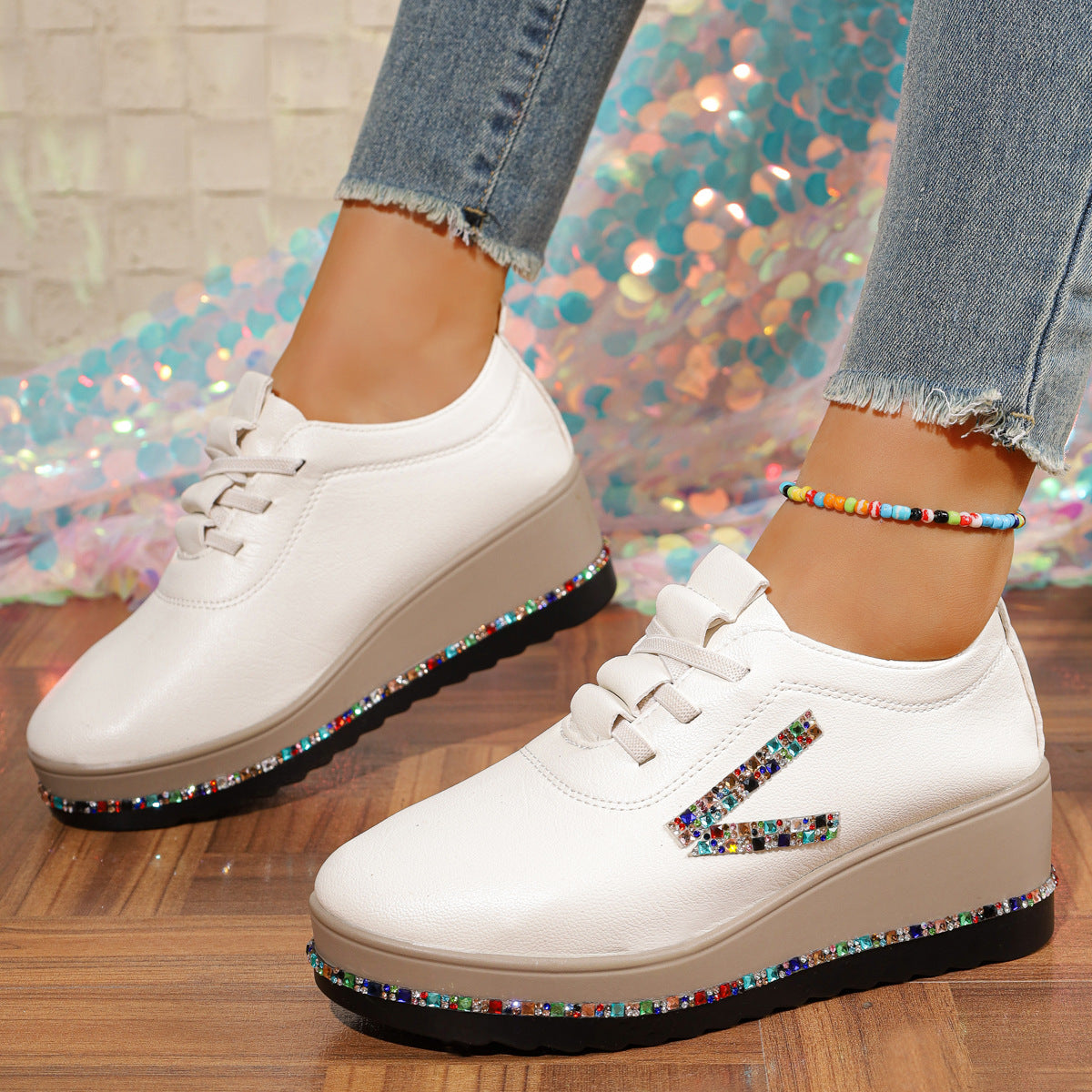White wedge sneakers with colorful rhinestone embellishments on the side and platform.