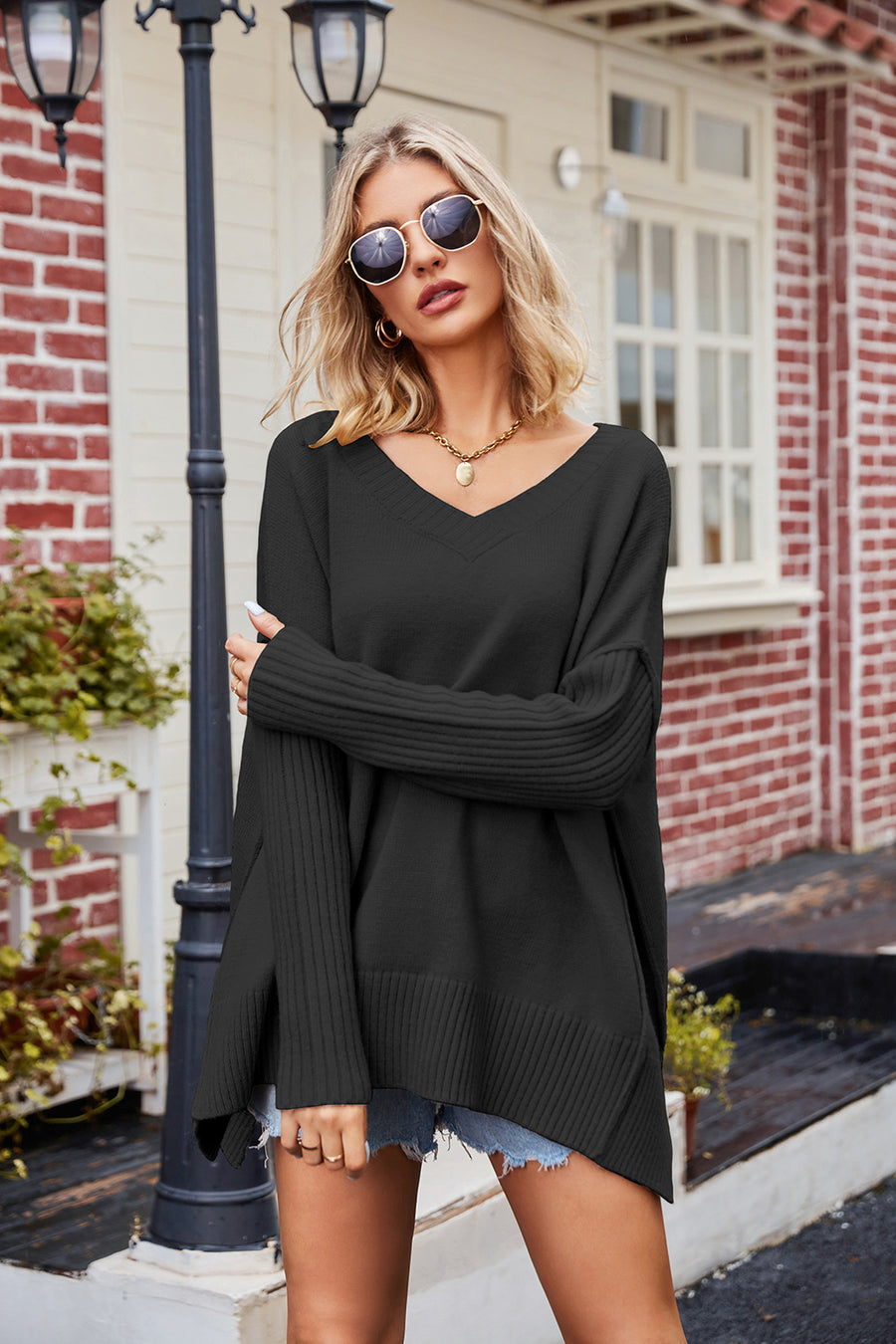 Black knit sweater with V-neck, ribbed sleeves, and asymmetric slit hemline