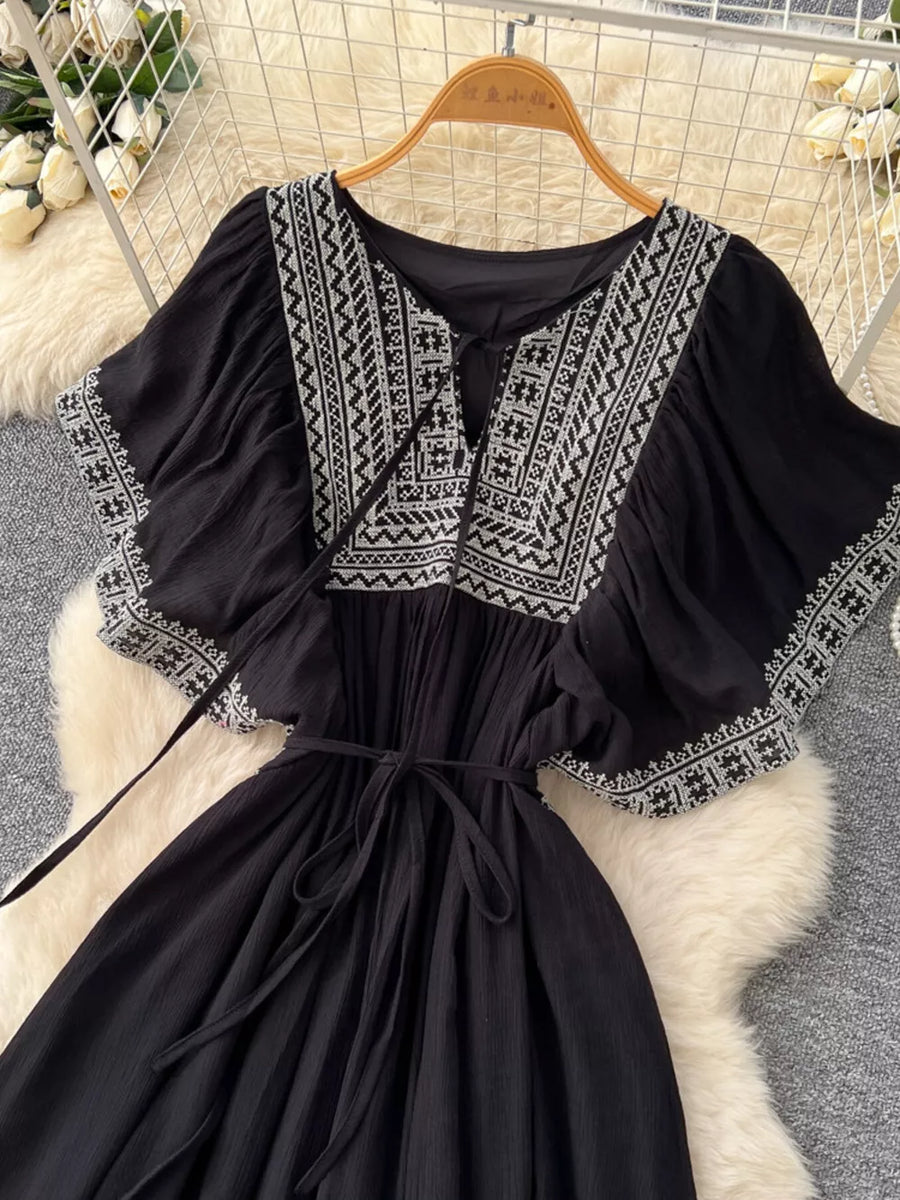 Black embroidered V-neck boho maxi dress with tie waist and flutter sleeves.