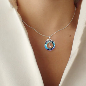 Infinity knot crystal pendant necklace in royal blue with a clear crystal accent.