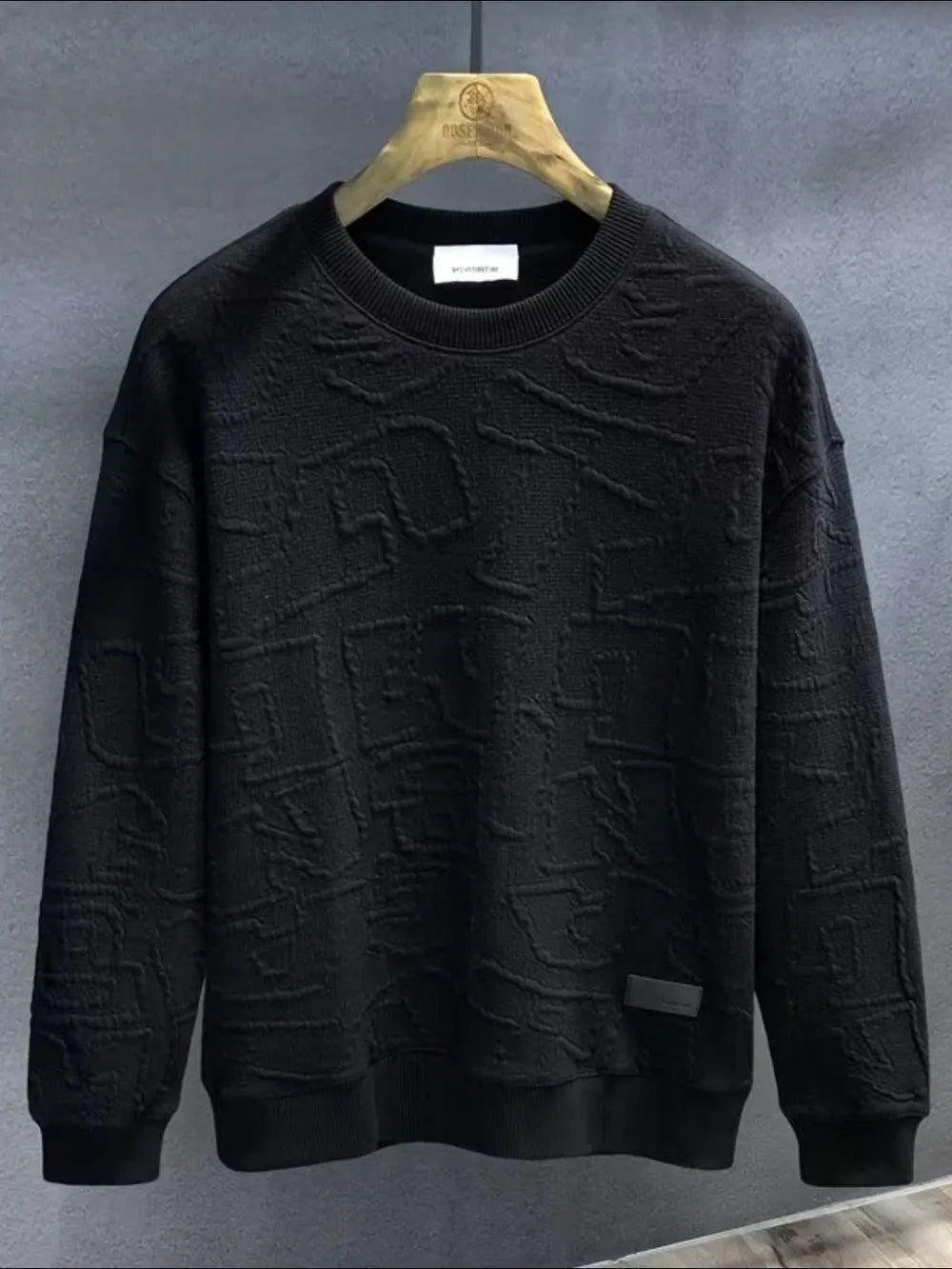 Black crewneck sweatshirt with embossed geometric texture and ribbed cuffs and hem.