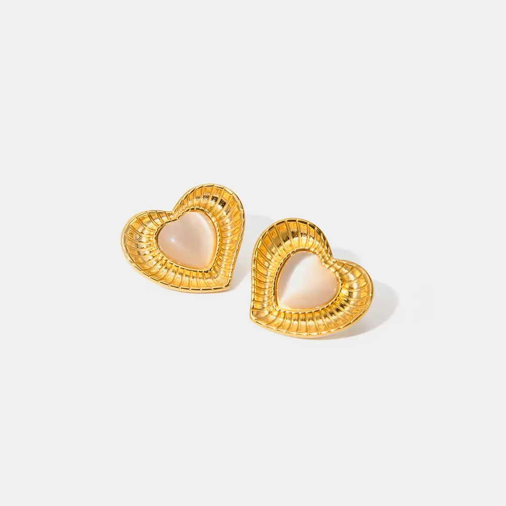 Golden heart stud earrings with a ribbed texture and a pale pink cabochon center.