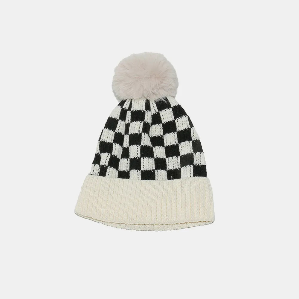 Checkerboard knit beanie with ivory ribbed cuff and faux fur pom.
