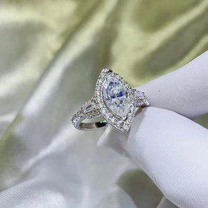 White gold marquise halo moissanite engagement ring with baguette and round accent stones.
