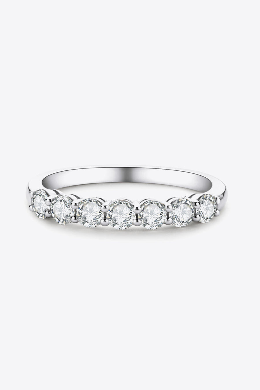 Silver band ring with seven round moissanite stones in a shared prong setting.