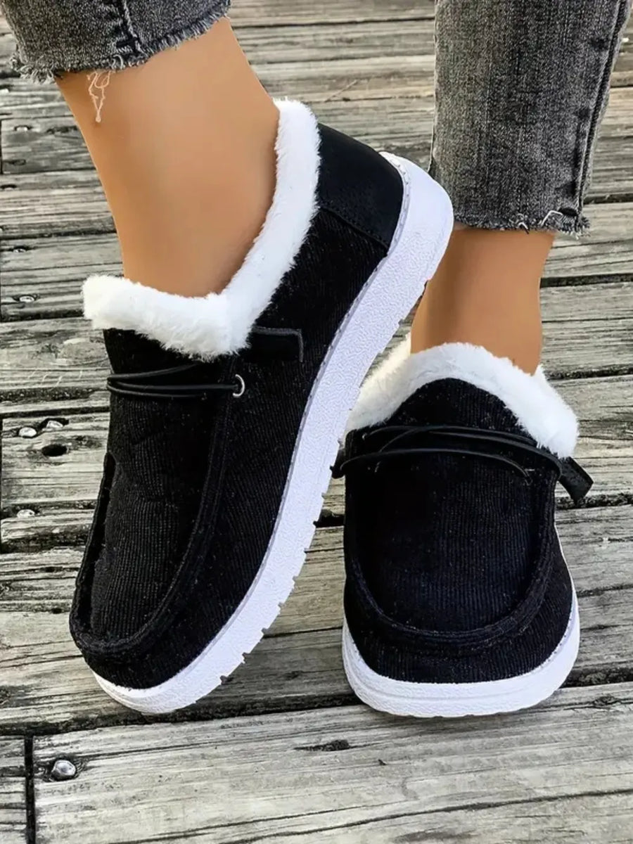 Black corduroy slip-on sneakers with white sherpa lining and white soles.