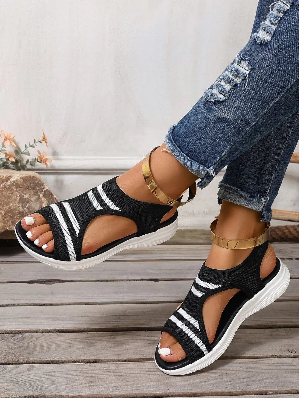 Black and white striped knit sport sandals with gold ankle straps.