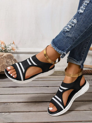 Black and white striped knit sport sandals with gold ankle straps.