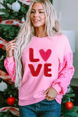 Pink sweatshirt with red sequin sleeves and "LOVE" appliqué.