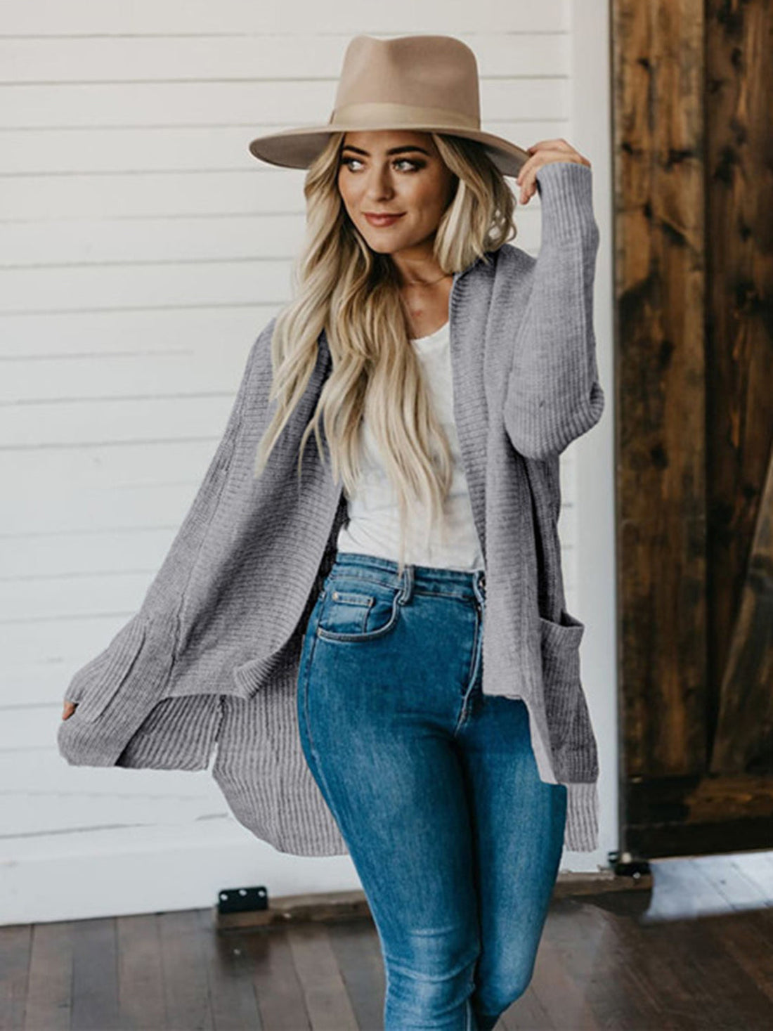 Drape-front ribbed knit cardigan in dark gray with pockets, styled with jeans and a hat.