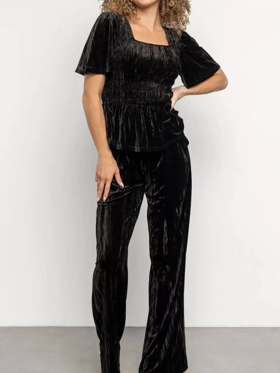 Black velvet two-piece set with smocked bodice and flutter sleeves, paired with wide-leg pants.