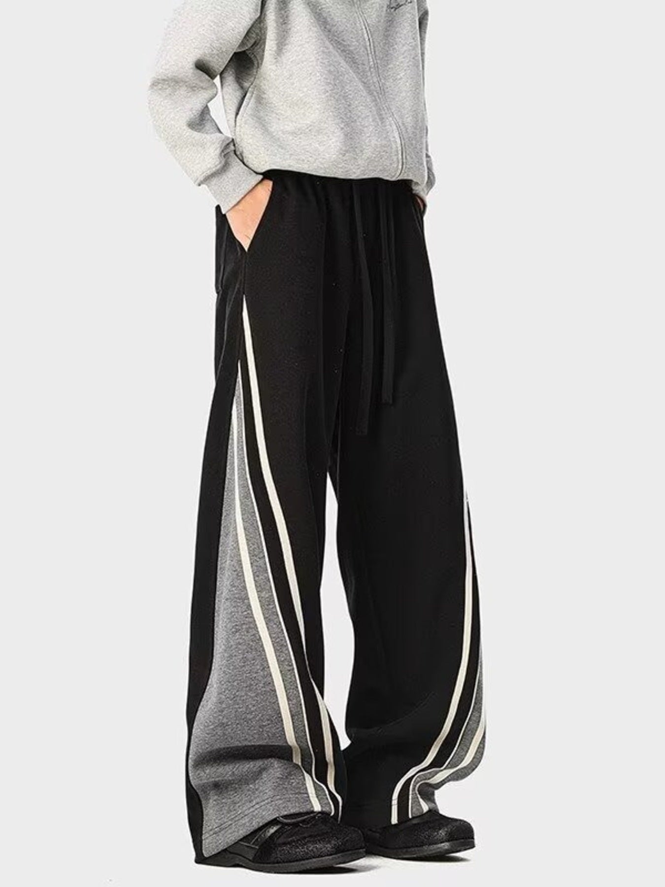 Men's black drawstring joggers with gray side panels and white stripes.