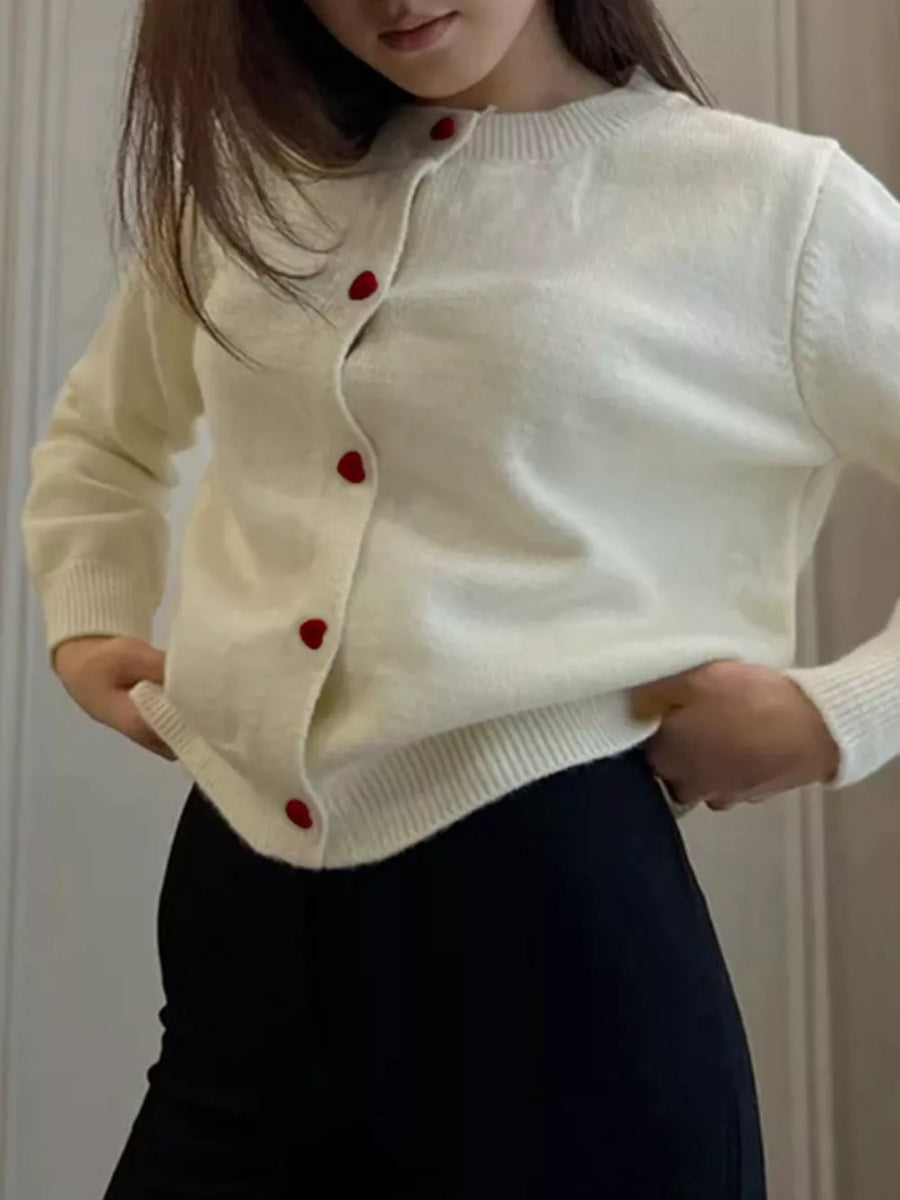 Cream knit cardigan with red heart buttons and crew neck.